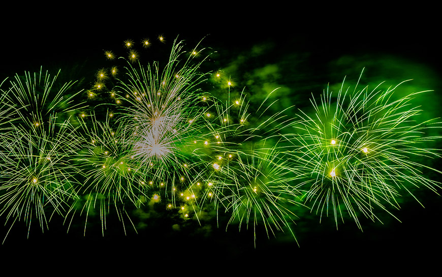 Green fireworks explode in the night sky