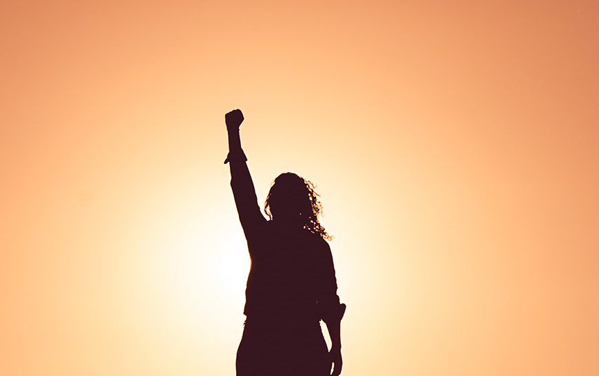 Silhouette of woman with clenched fist held up in triumph