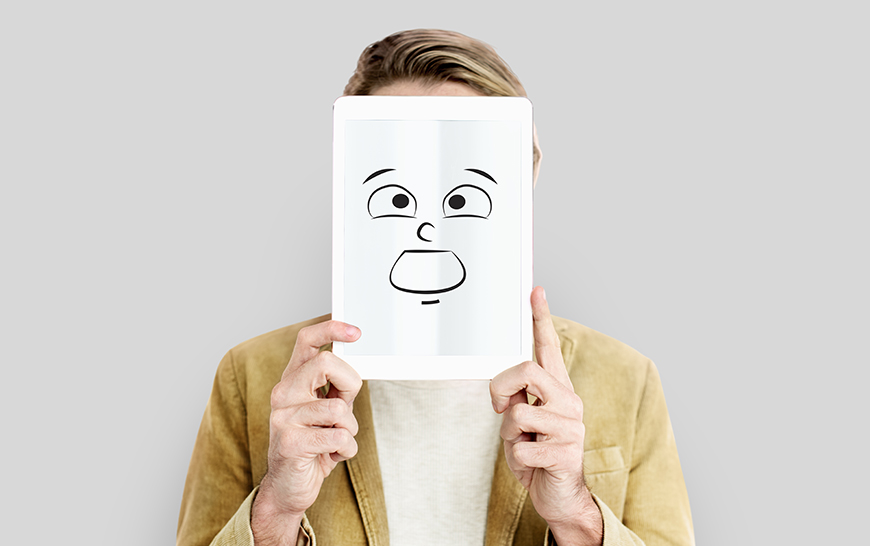 A person holds a cartoon of a face in front of their face